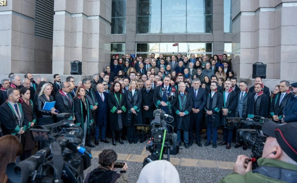 A group of people in official robes stand in front of a courthouse.